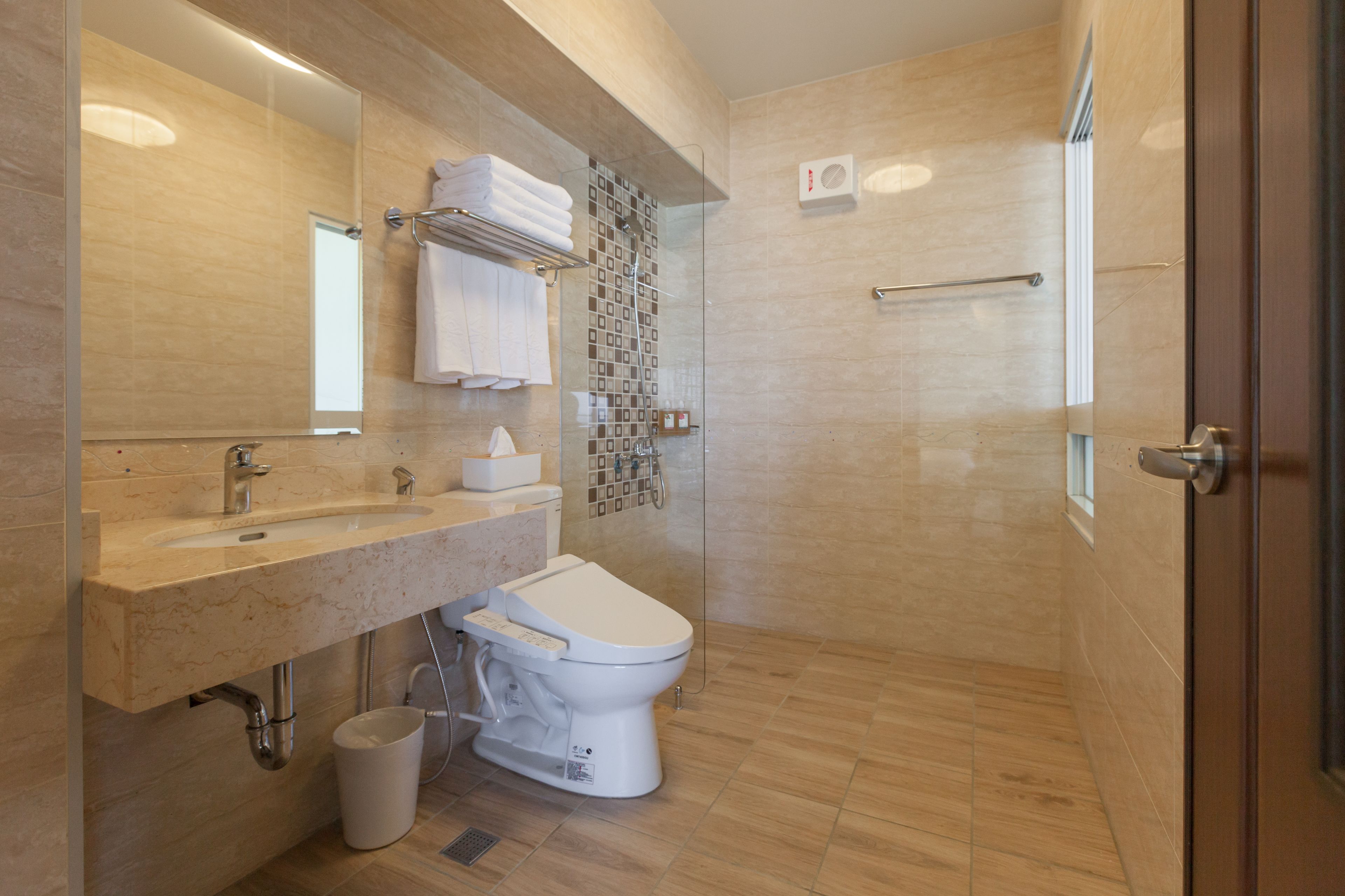 Un baño moderno con lavamanos, inodoro y ducha con mampara de vidrio.