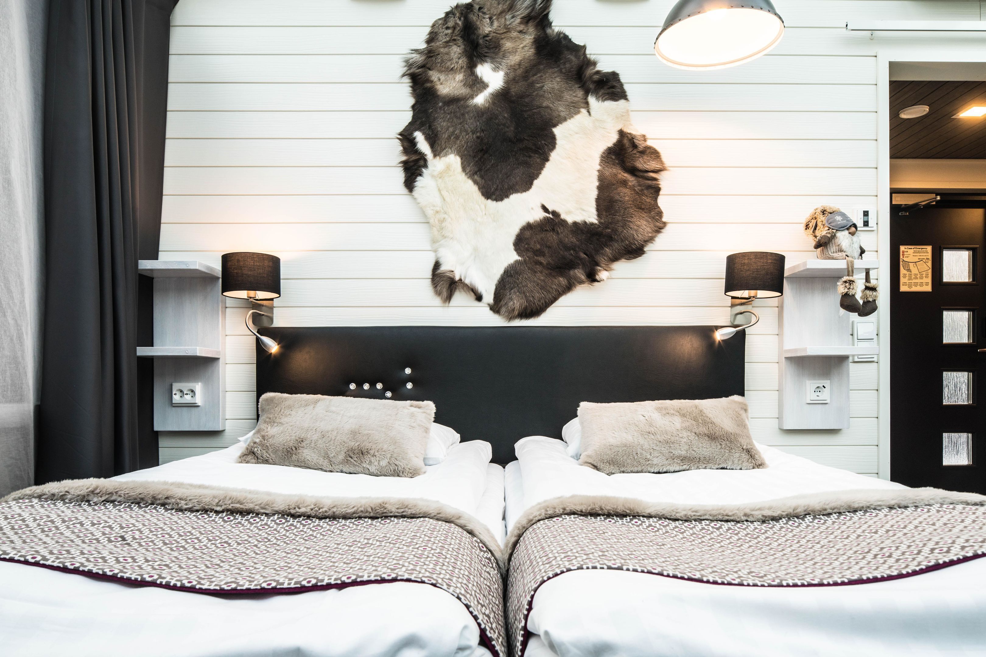 Ett modernt hotellrum med en stor säng, en mjuk matta och ett upphängt djurhuvud på väggen.