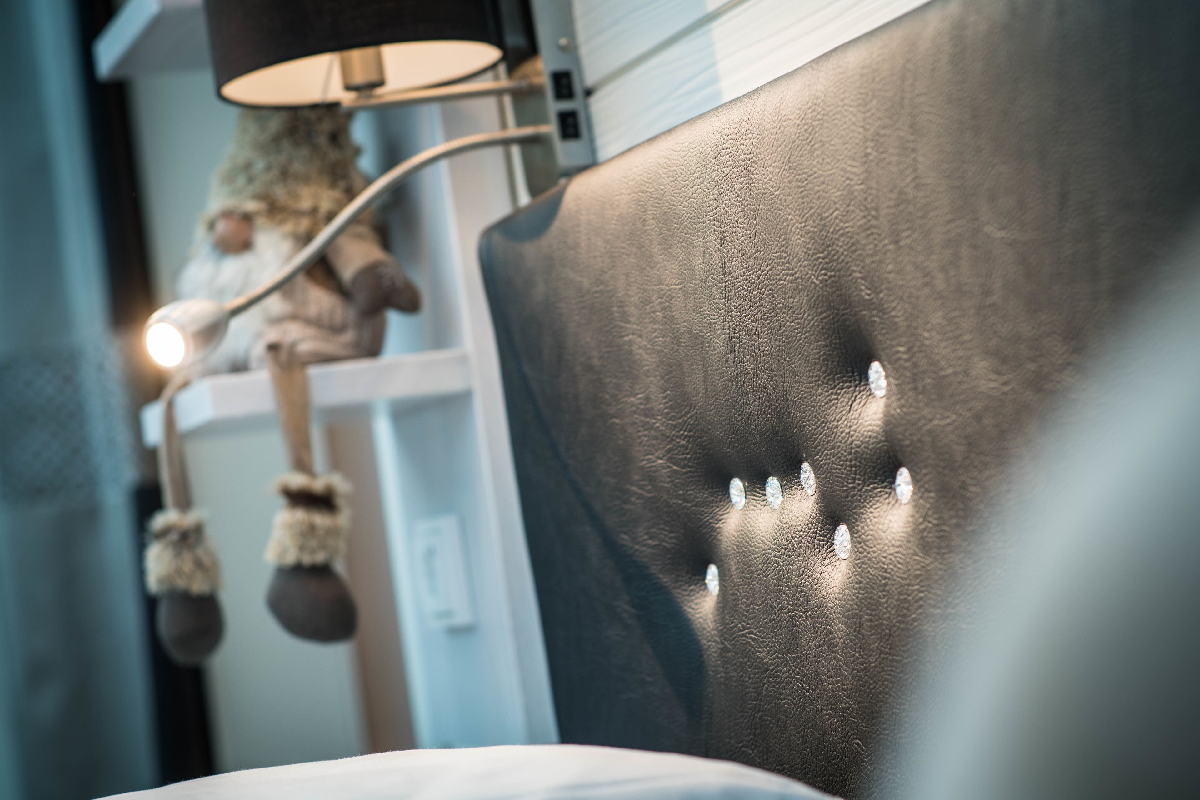 A close-up of a room's headboard with a textured surface and decorative studs.