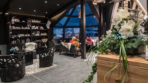 A modern interior with a high ceiling, a large window, and a variety of seating arrangements. - Santa's Igloos Arctic Circle (Rovaniemi)