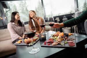 Una mesa de comedor con diversos platos y copas de vino, ubicada en un interior moderno con ventanales amplios.