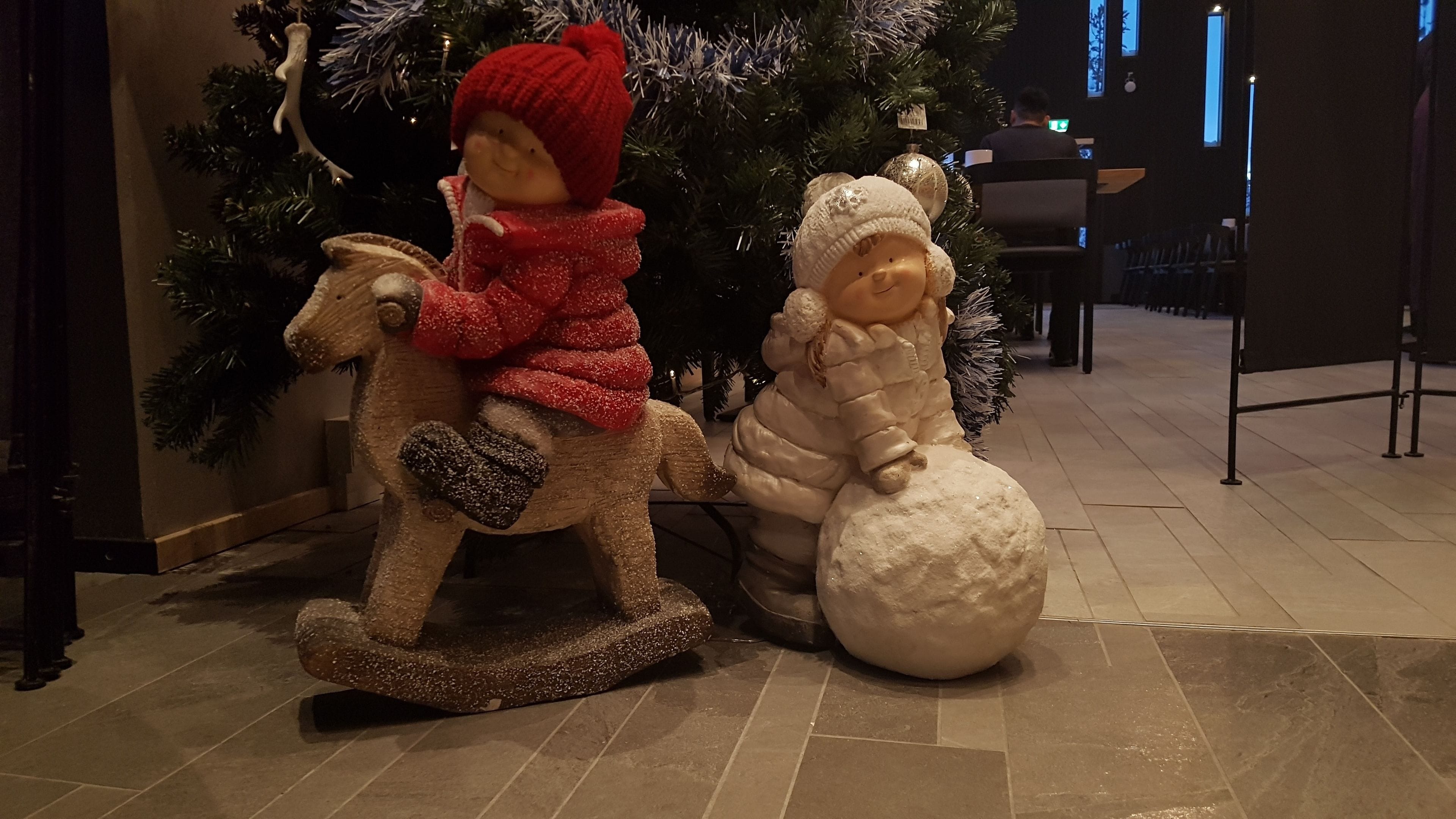 A decorative Christmas scene with a rocking horse and a snowman figure.
