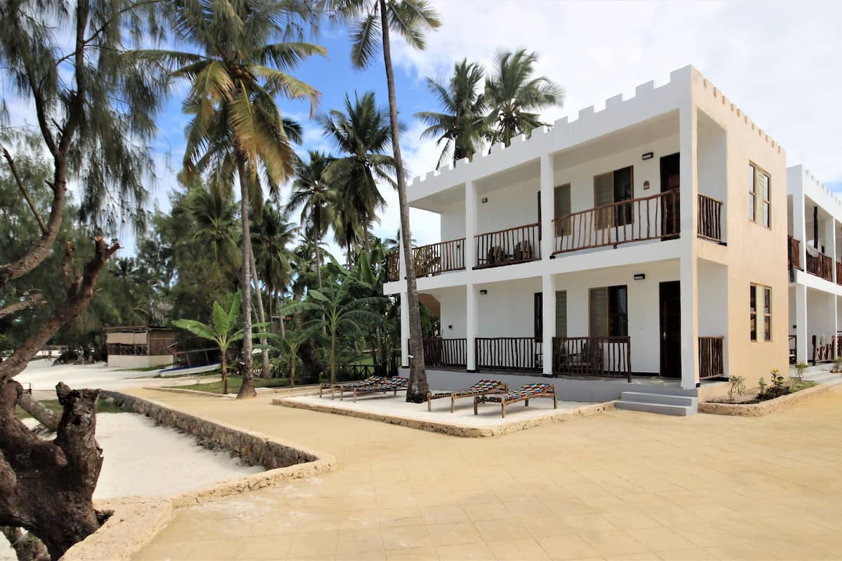 A multi-story hotel with balconies, a paved courtyard, and palm trees.