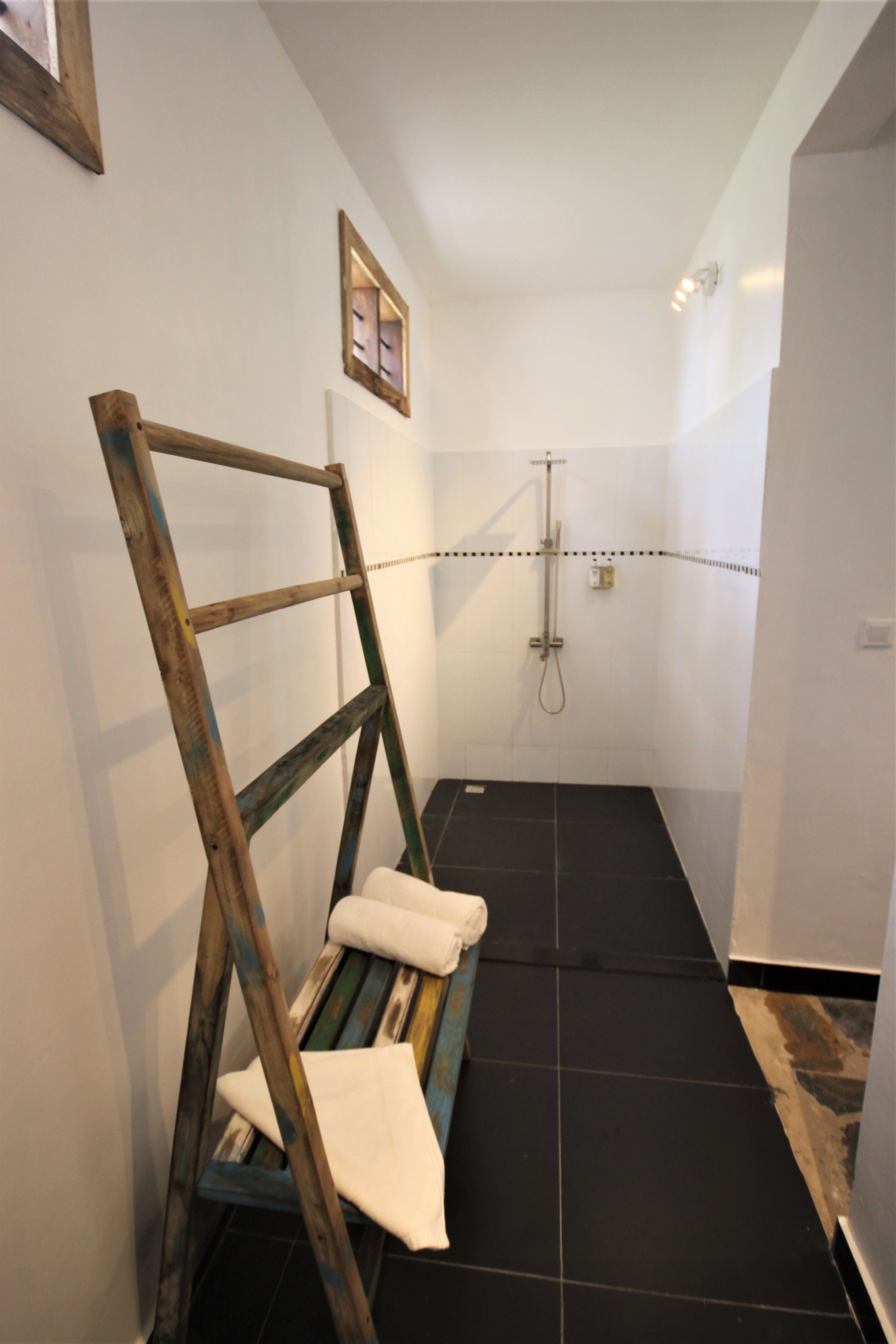 A bathroom with a shower, a wooden ladder, and a towel.