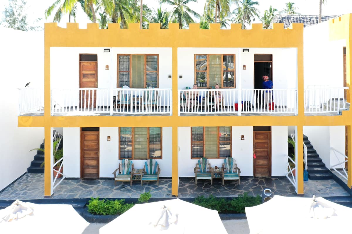 A two-story building with balconies, wooden doors, and a stone-paved courtyard.
