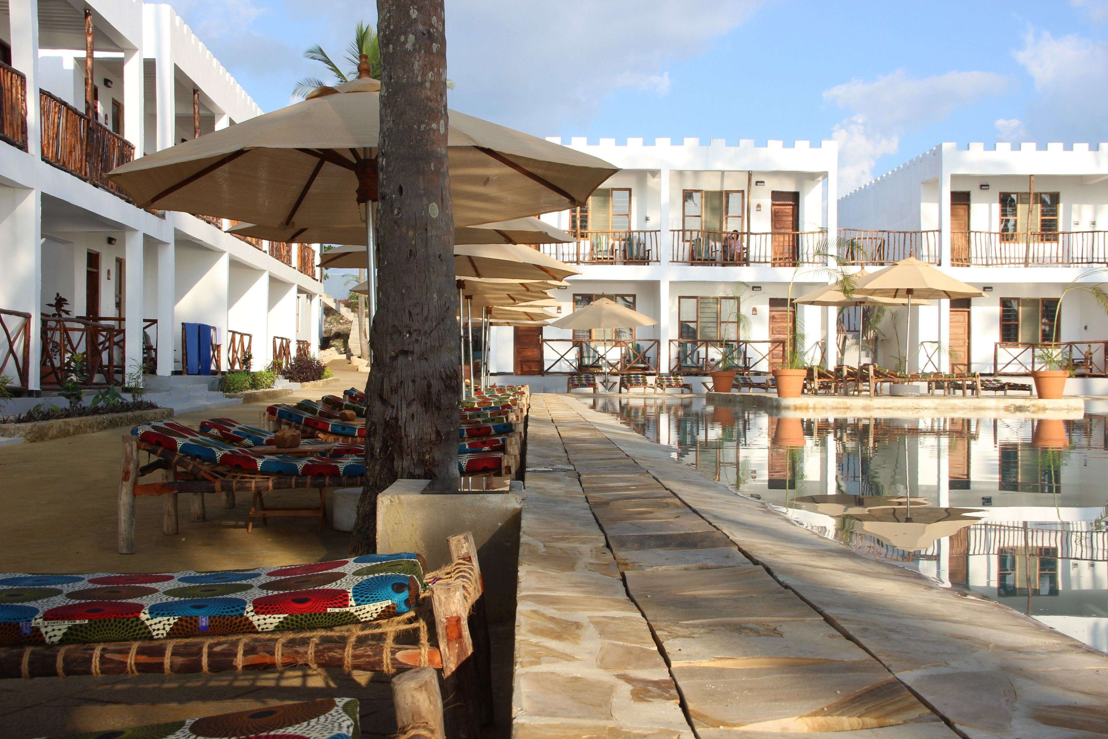 A resort with a pool, outdoor seating, and white buildings with balconies.