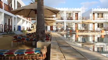 A resort with a pool, outdoor seating, and white buildings with balconies.