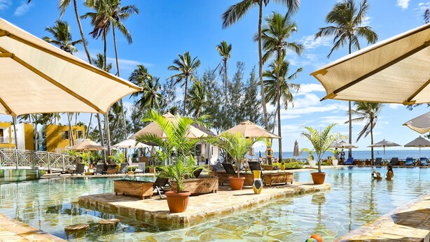 A pool area with lounge chairs, umbrellas, and potted plants. - Zanzibar Bay Resort (Marumbi)