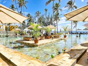 A pool area with lounge chairs, umbrellas, and potted plants. - Zanzibar Bay Resort (Marumbi)