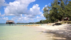 A beach with clear water, a thatched-roof structure, and a pier extending into the sea. - Zanzibar Bay Resort (Marumbi)
