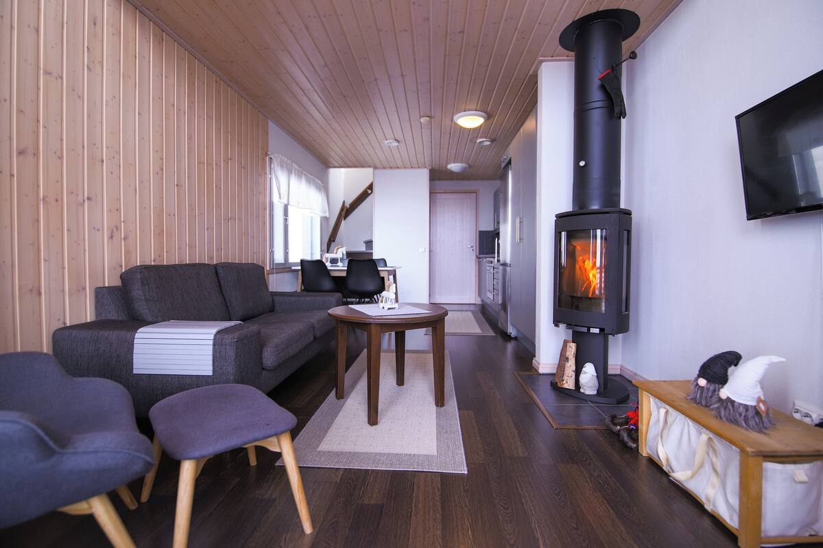 Un salon moderne avec un canapé, des fauteuils, une petite table et un poêle à bois.
