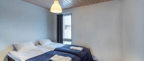 A hotel room with two beds, a window, and a wooden ceiling.