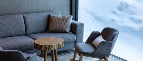 A modern living room with a grey sofa, a wooden coffee table, and a rocking chair.