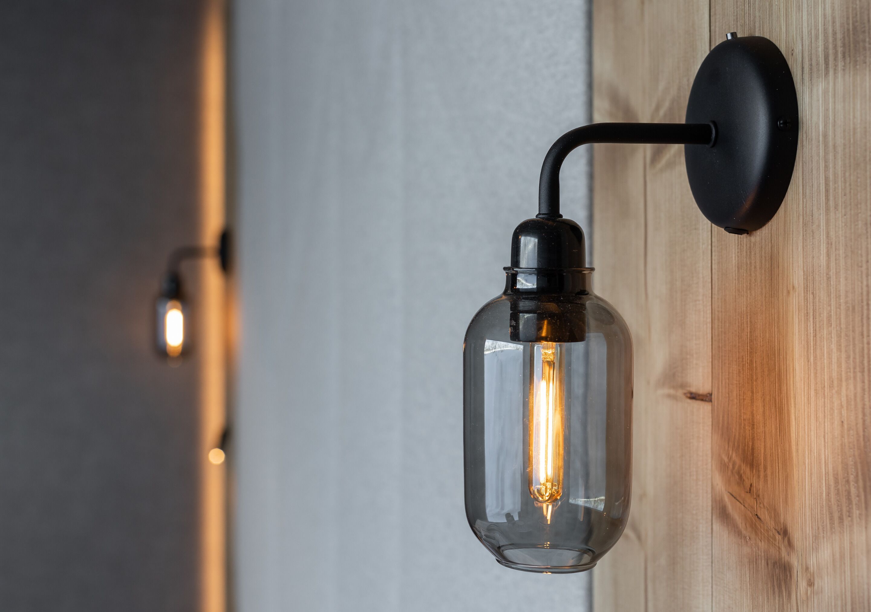 A wall-mounted light fixture with a clear glass enclosure and a visible filament bulb.