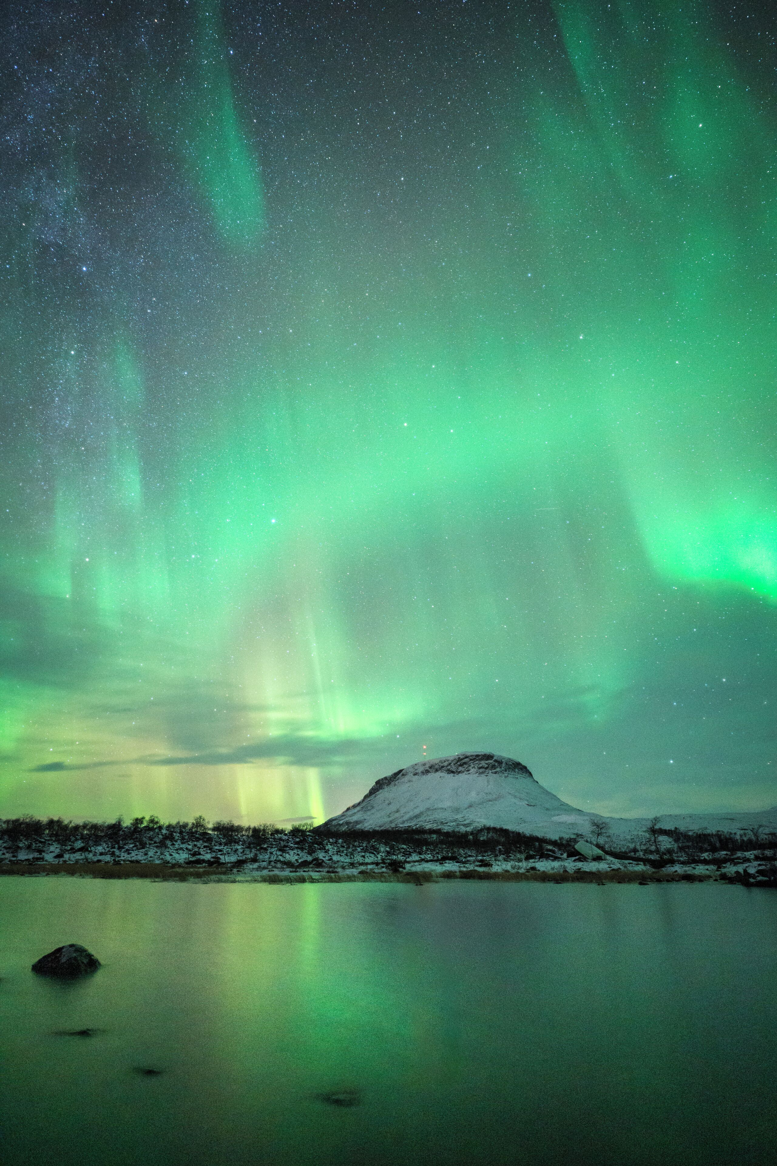 A serene night sky with the Northern Lights over a snow-covered landscape and a calm lake.