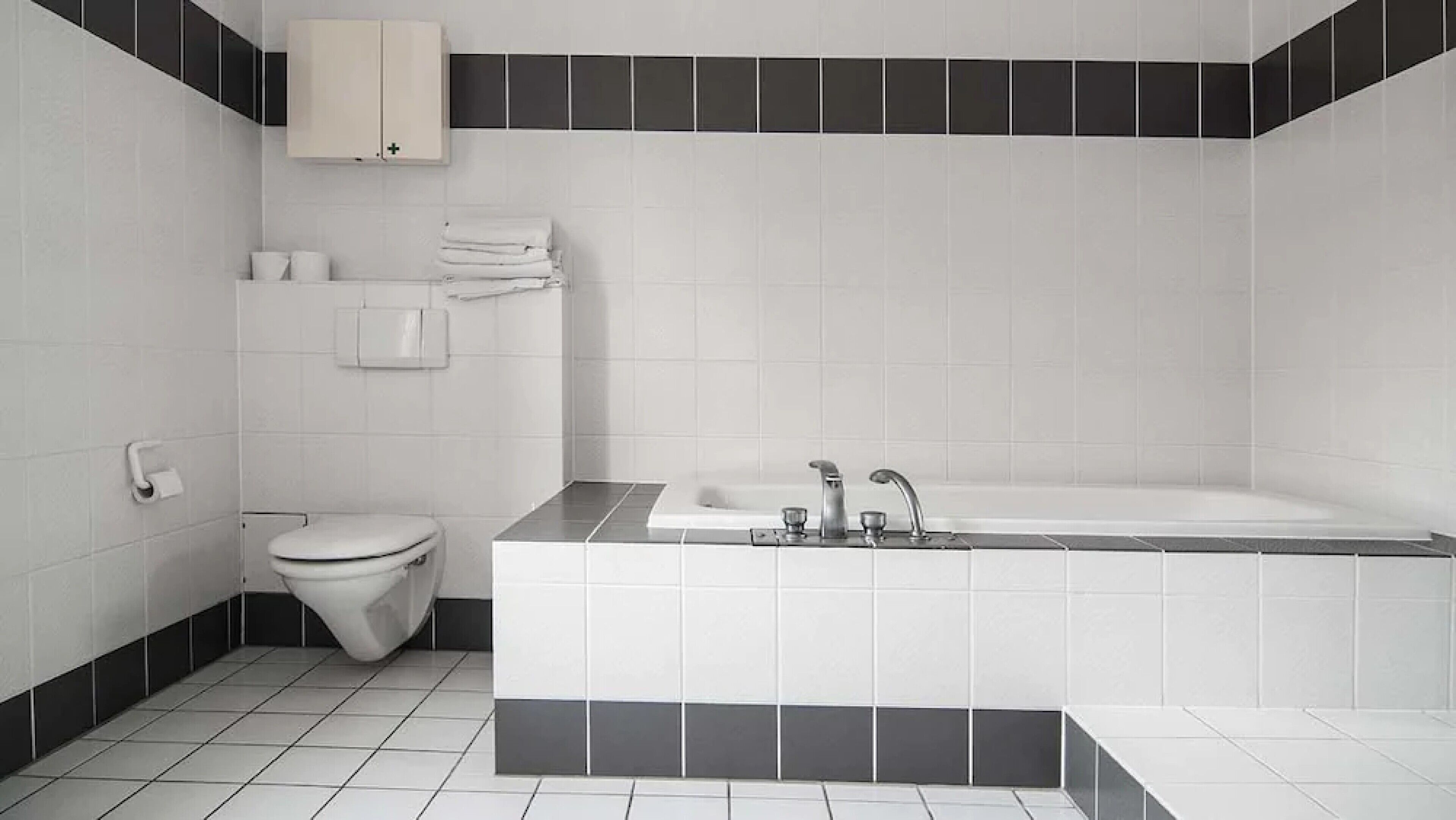 Une salle de bain moderne avec des toilettes blanches, un lavabo et une baignoire.