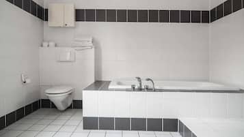 Une salle de bain moderne avec des toilettes blanches, un lavabo et une baignoire.
