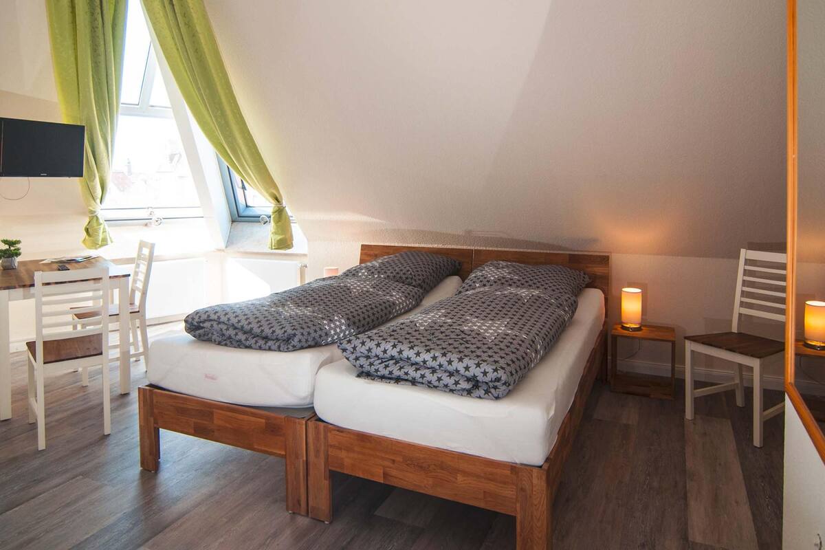 Une chambre à coucher avec un lit en bois, un bureau, une chaise et un téléviseur fixé au mur.