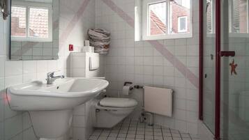 Un baño con lavamanos, inodoro y cabina de ducha de vidrio.