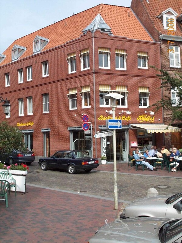 Ein rotes Backsteinhaus mit mehreren Fenstern und einem Schild für 'Bäckerei & Café'.