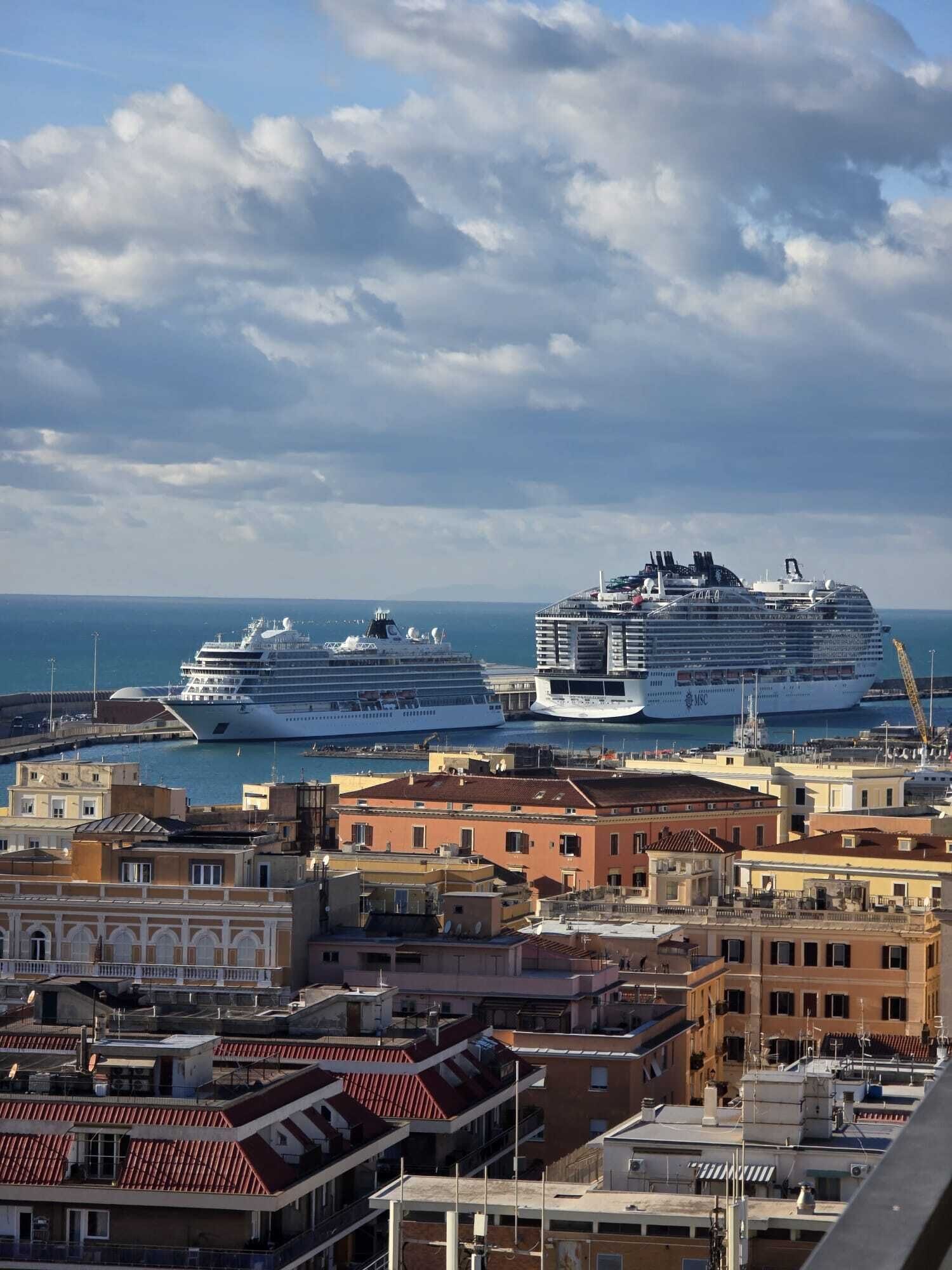 A harbor with two large cruise ships docked, surrounded by historic buildings with red-tiled roofs.