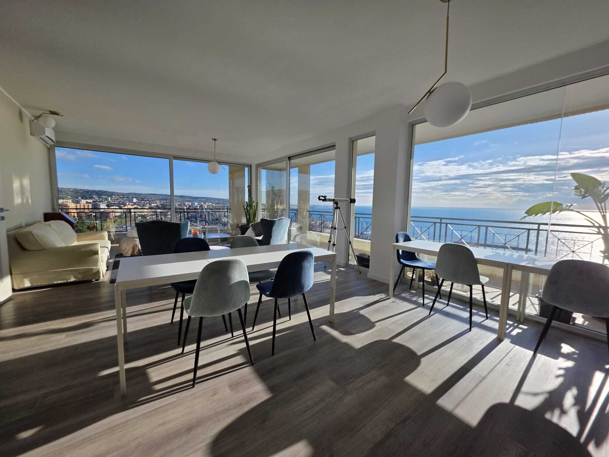 Amplia sala de estar con balcón que da a una vista panorámica de la ciudad y el mar.