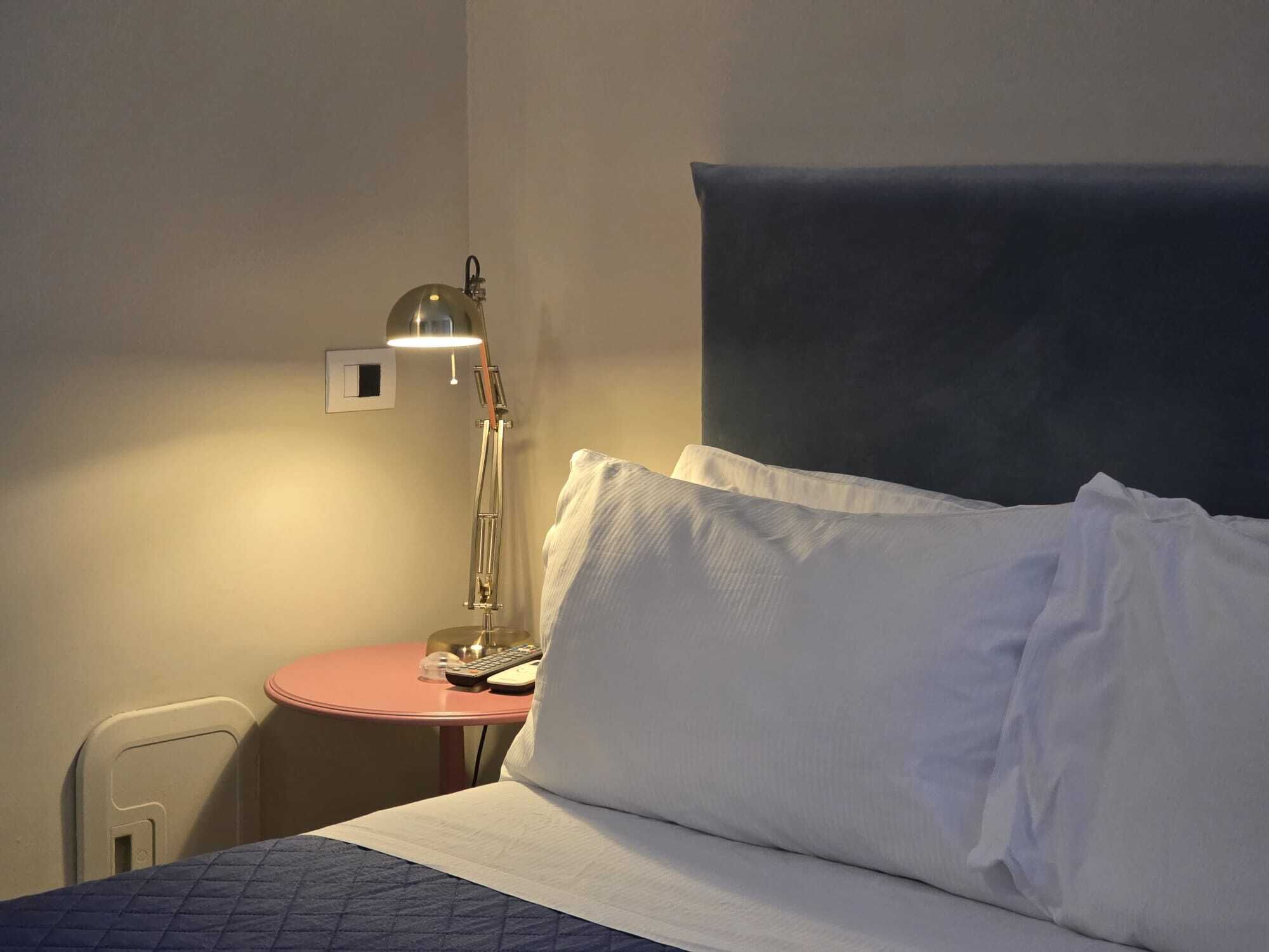 Een hotelkamer met een bed, een nachtkastje met een lamp en een kleine ronde tafel.
