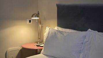 Een hotelkamer met een bed, een nachtkastje met een lamp en een kleine ronde tafel.