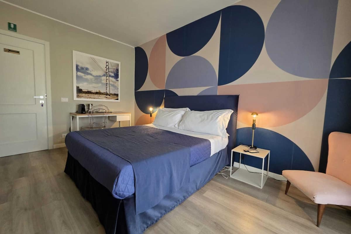 Un dormitorio con cama, mesitas de noche, un escritorio y una silla.