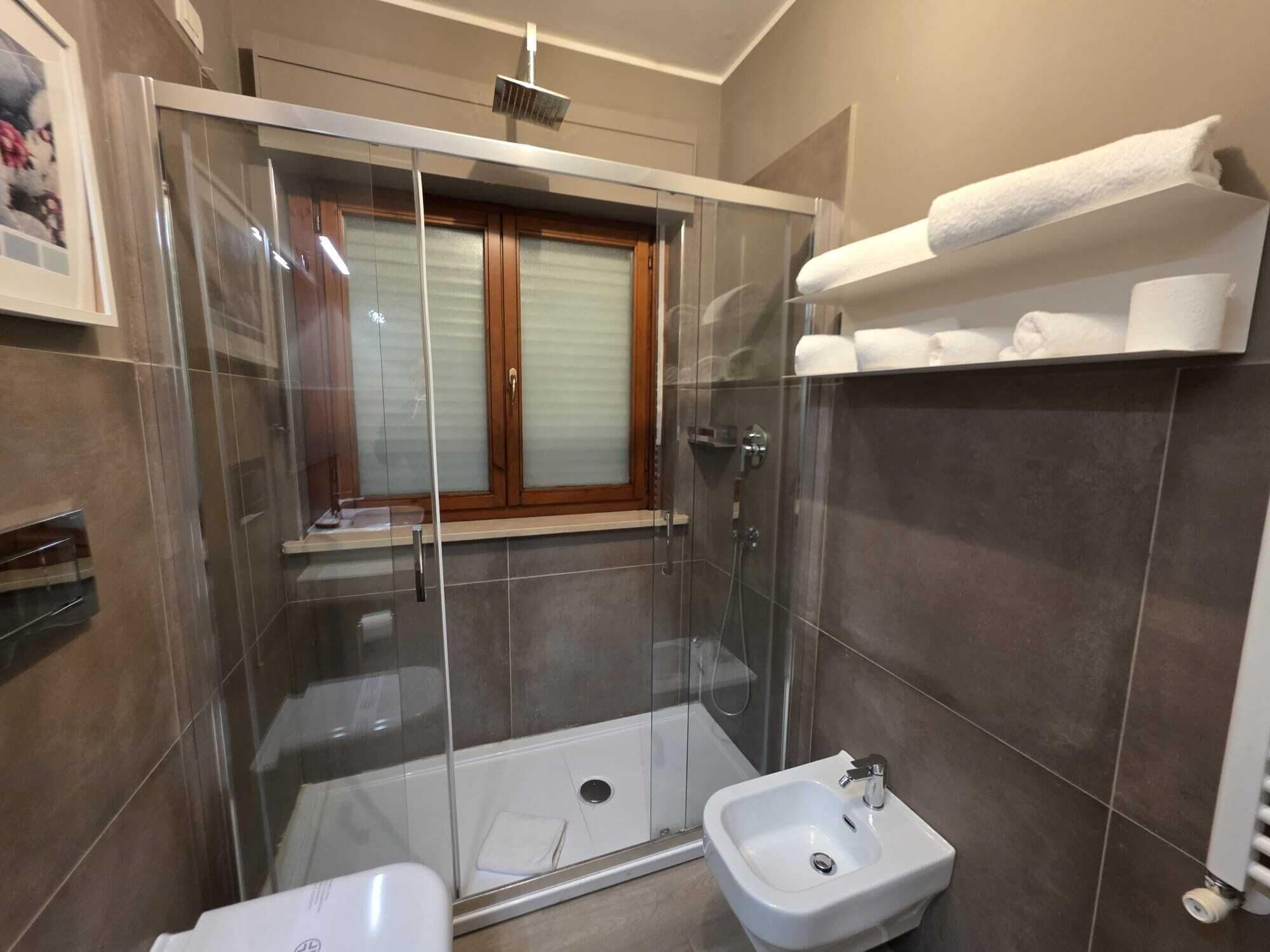 Ein modernes Badezimmer mit einer Glaskabine zur Dusche, einer Badewanne und einem Waschbecken.