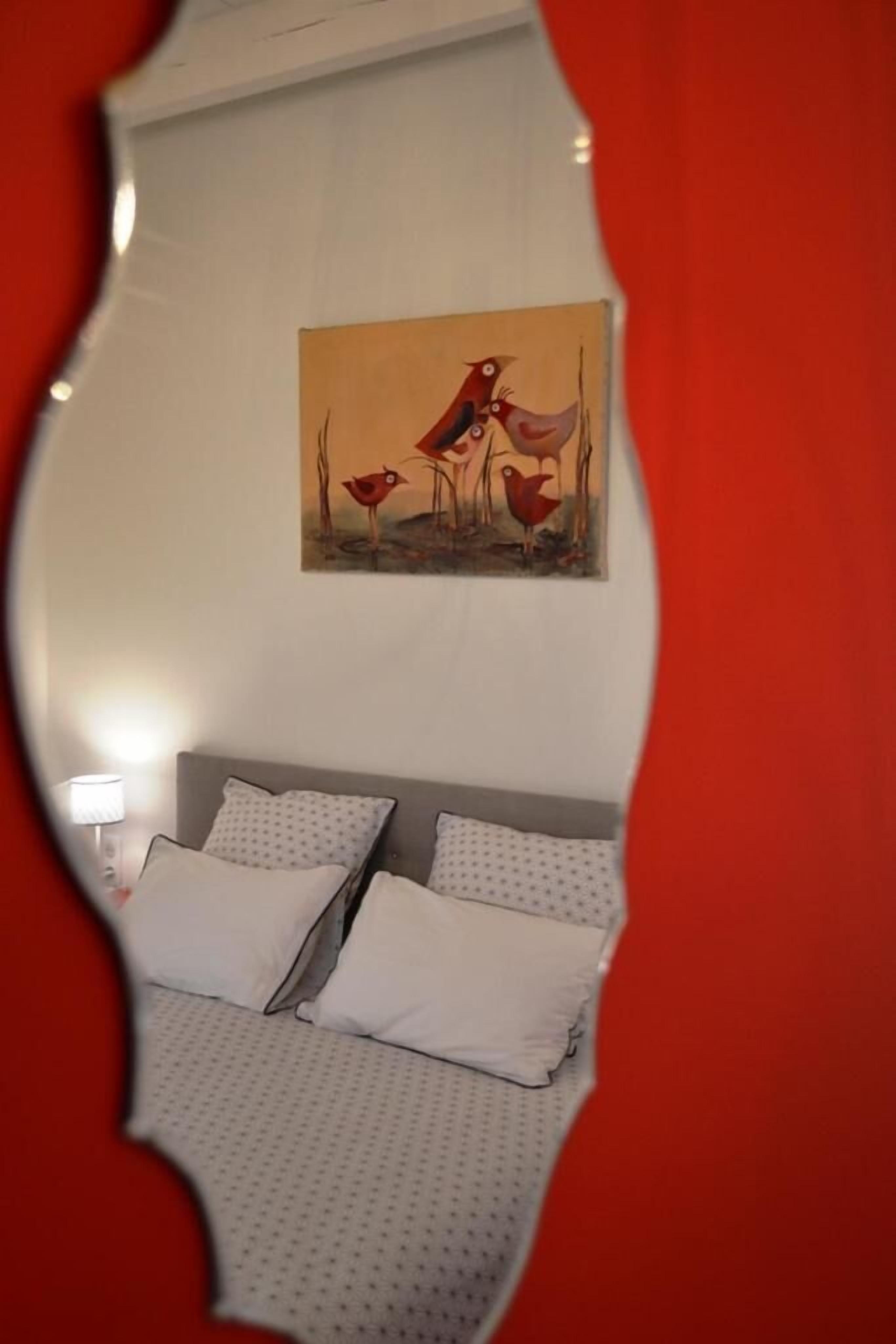 A bedroom with a bed, pillows, a nightstand, and a wall-mounted painting.