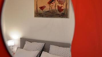 A bedroom with a bed, pillows, a nightstand, and a wall-mounted painting.