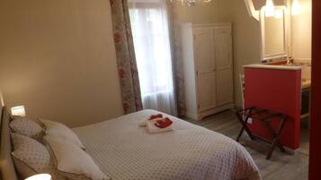A bedroom with a bed, a wardrobe, a desk, and a mirror.