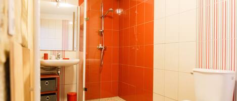 A bathroom with a shower, toilet, sink, and mirror.
