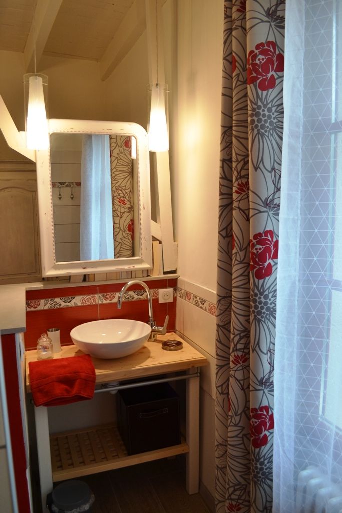Un baño con un lavabo blanco, un espejo y una toalla roja.