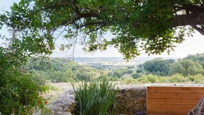 Un muro de piedra con una terraza de madera y vistas a un valle exuberante.