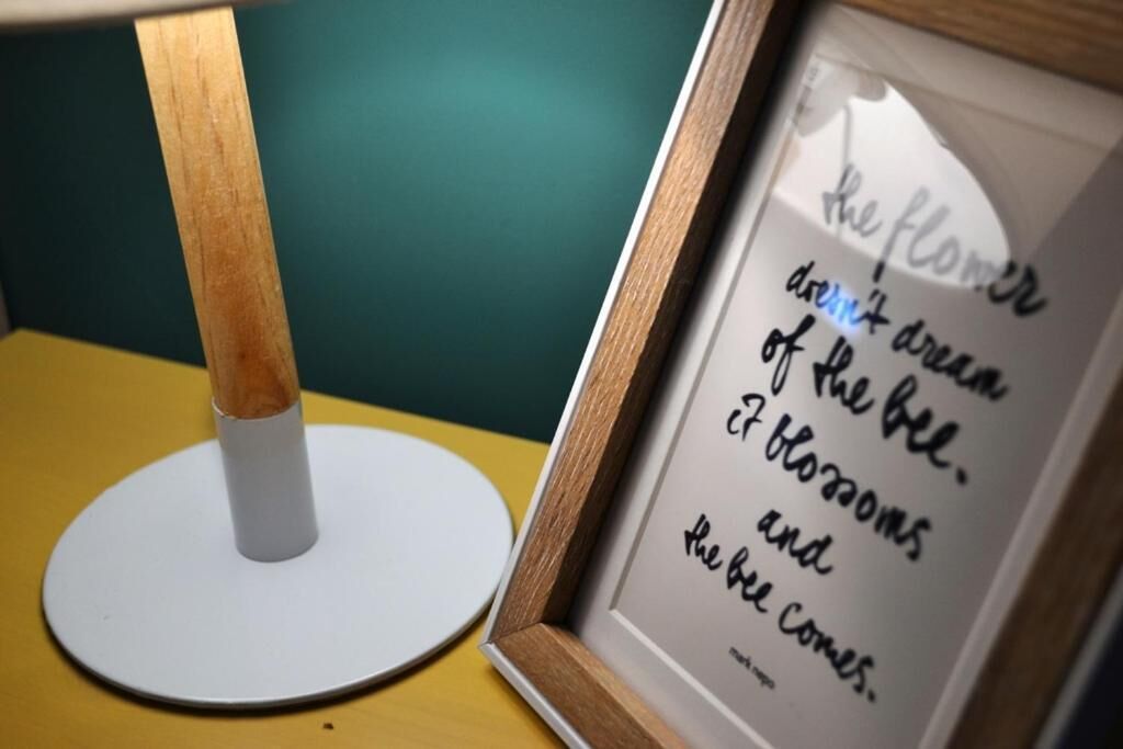 A framed quote on a table with a lamp.