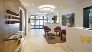 A reception area with a modern design, featuring a reception desk, seating area, and a wall-mounted calendar. - Hotel Gasthof zum Ochsen (Arlesheim)