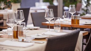 A dining table set with wine glasses, water glasses, and cutlery, with a wicker chair in the foreground. - Hotel Gasthof zum Ochsen (Arlesheim)