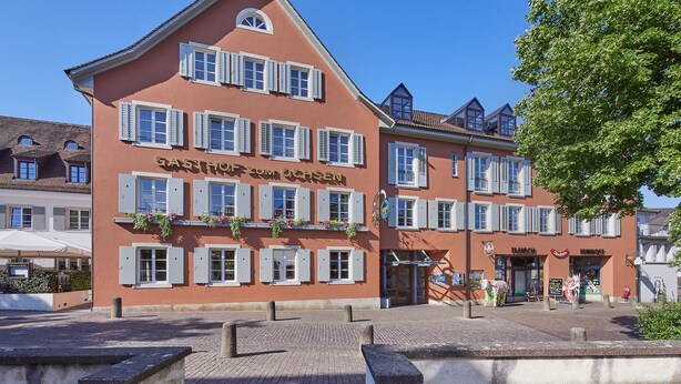 A traditional European building with multiple windows and a sign that reads "Gasthof Zum Ochsen". - Hotel Gasthof zum Ochsen (Arlesheim)