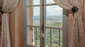 Una habitación con un ventanal grande, cortinas y vistas a un paisaje verde.