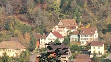 A hillside village with traditional houses, a prominent rock formation, and a small tower.