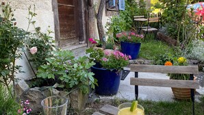 A garden patio with a table set for two, featuring drinks and snacks. - Maison des 5 Temps - Chambres Dhôtes de Charme à Ferrette (Ferrette)