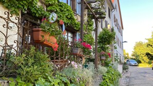 A traditional European building with ivy-covered walls, a cobblestone pathway, and a parked car. - Maison des 5 Temps - Chambres Dhôtes de Charme à Ferrette (Ferrette)