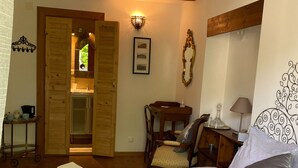 A cozy bedroom with a bed, a desk, and a bathroom visible through an open door. - Maison des 5 Temps - Chambres Dhôtes de Charme à Ferrette (Ferrette)