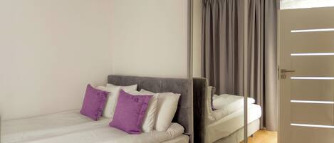 A bedroom with a bed, a mirror, and a door.