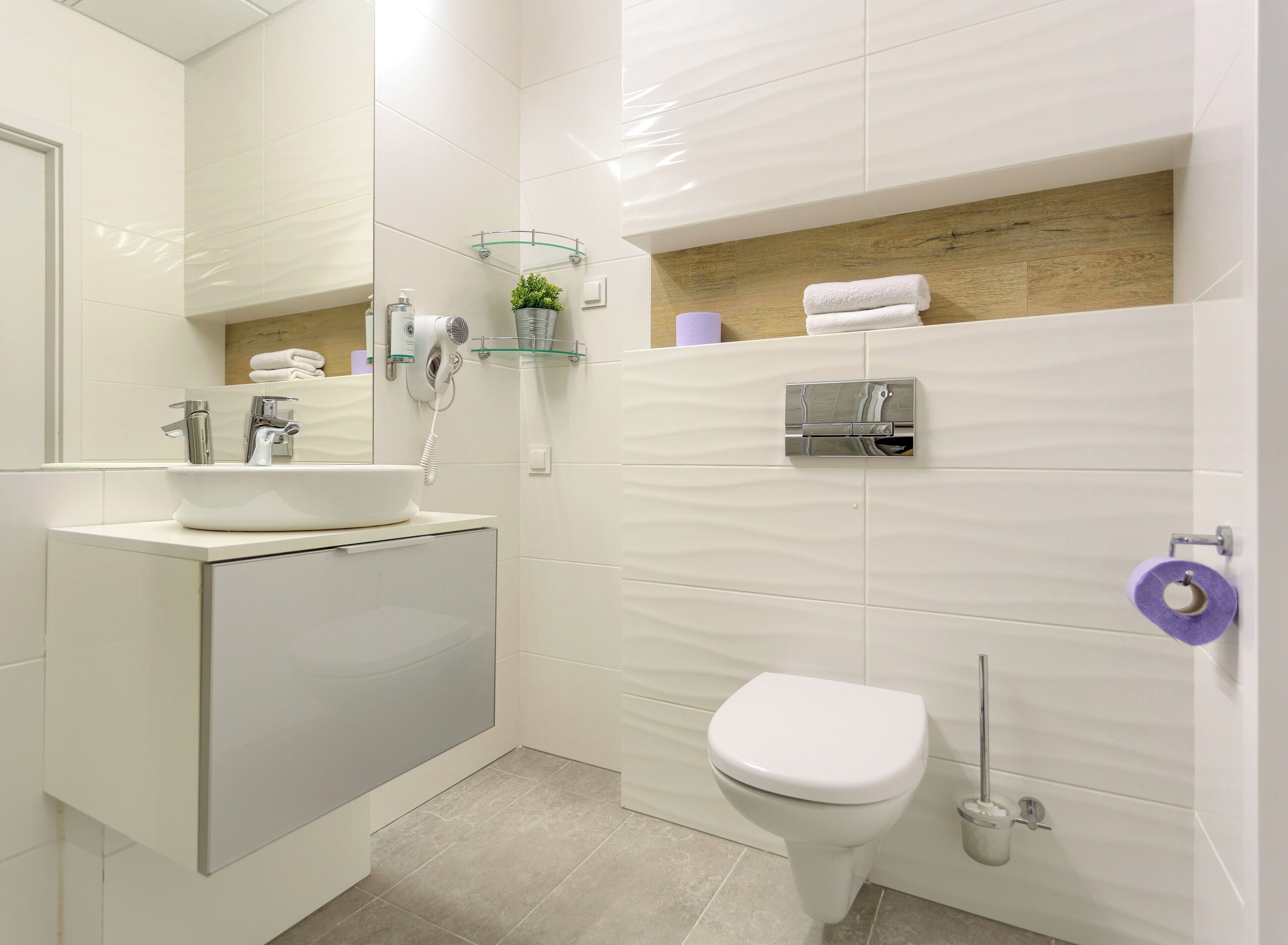 Une salle de bain moderne avec un lavabo blanc, des toilettes et un espace douche.