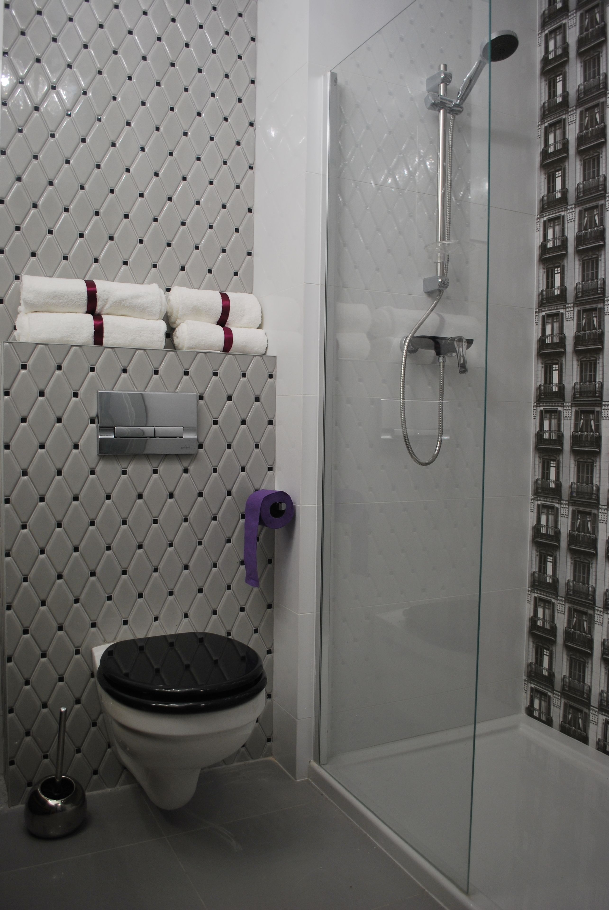 A bathroom with a toilet, a shower, and a toilet paper holder.