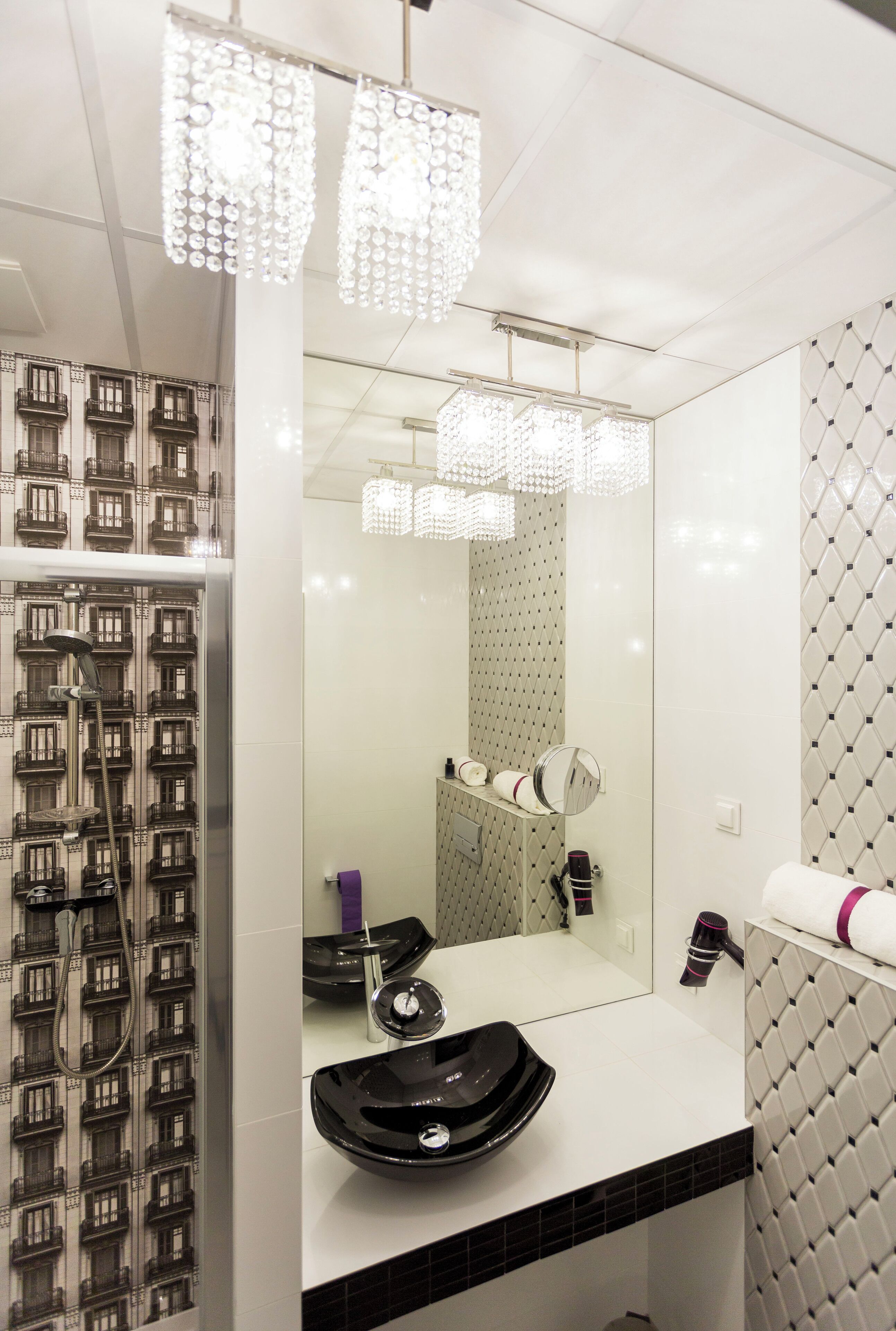 A modern bathroom with a large mirror, a black sink, and a shower with a patterned wall.