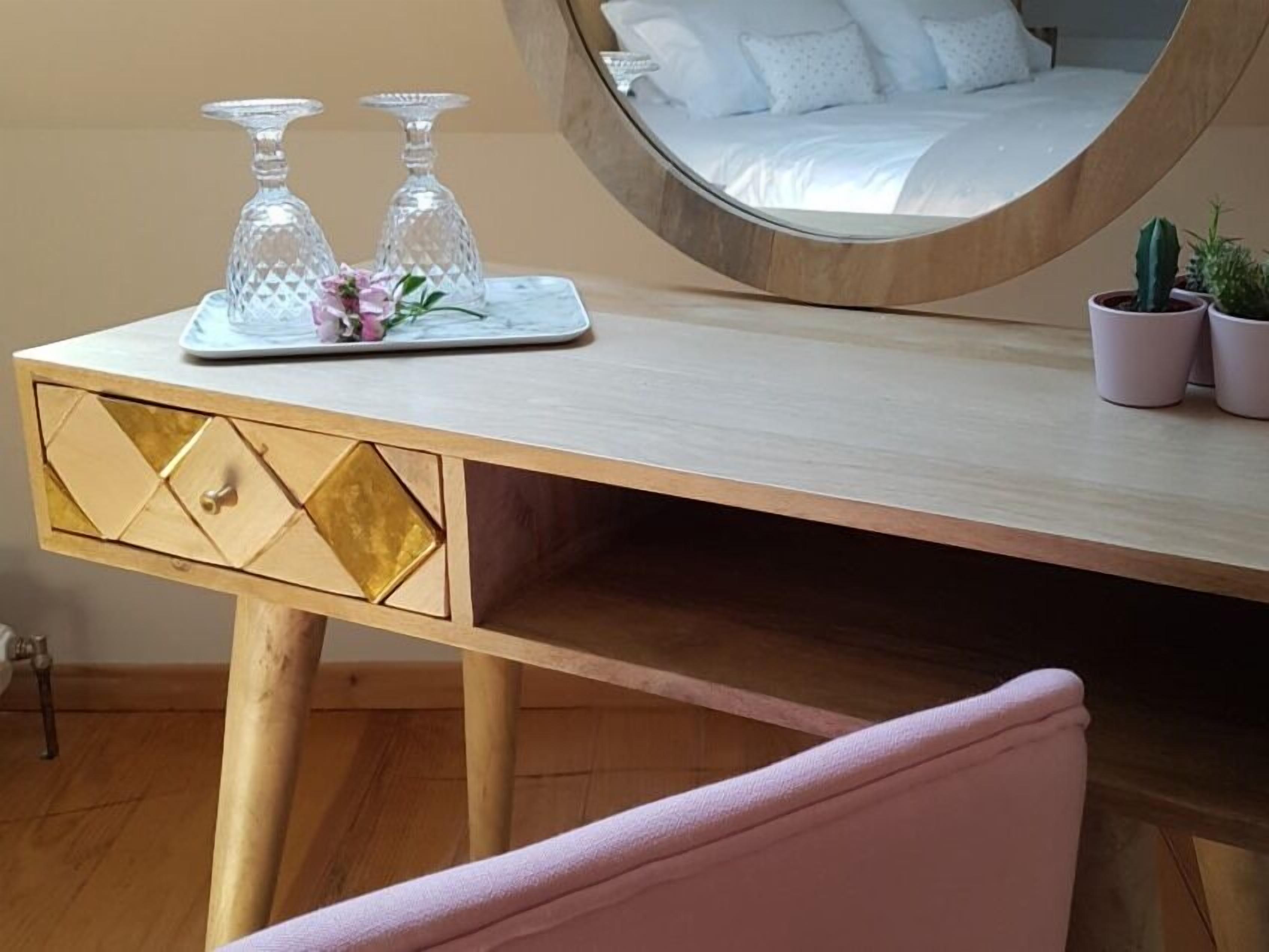 Un dormitorio con cama, una mesita de noche con cristalería decorativa y una planta en maceta.